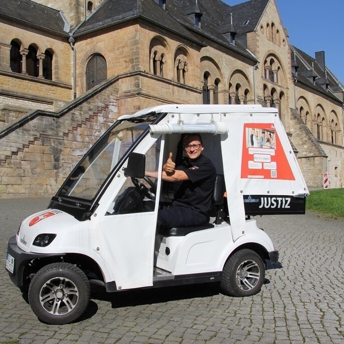 Foto zeigt einen Justizwachtmeister in einem Eletromobil